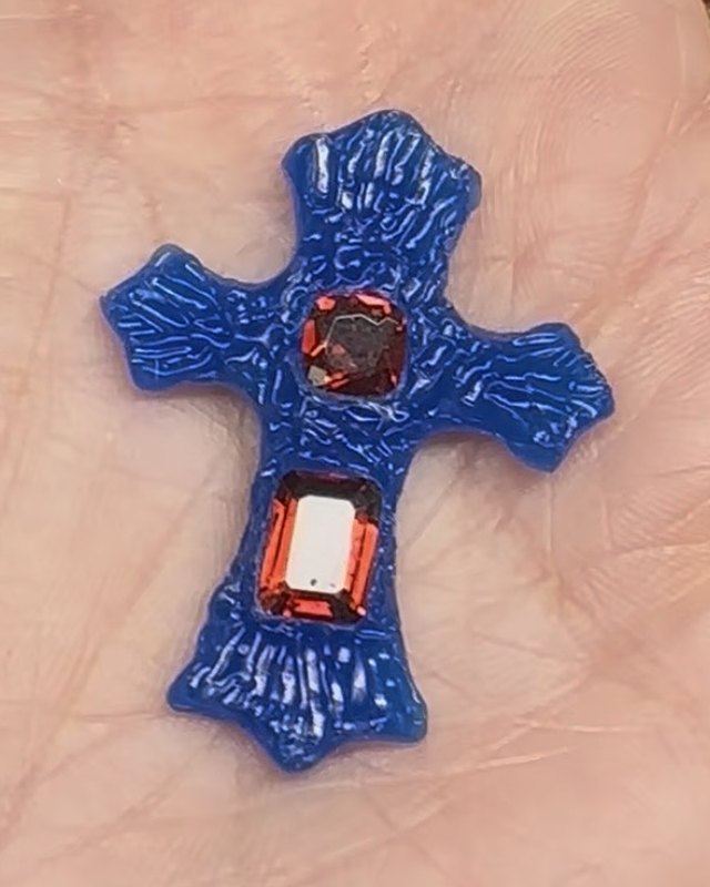 The first progress shot of the cross in blue wax, resting in a palm, with the two garnets in place