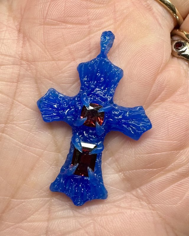 The final blue wax design of the cross, with both garnets held in wax claws, resting in a palm