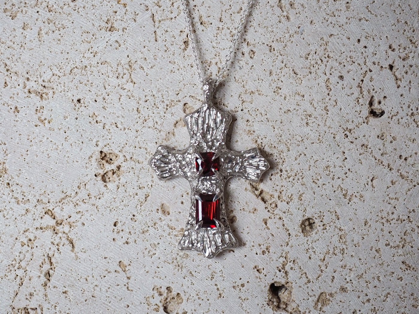 A handcrafted sterling silver cross pendant set with two garnets, on a fine chain