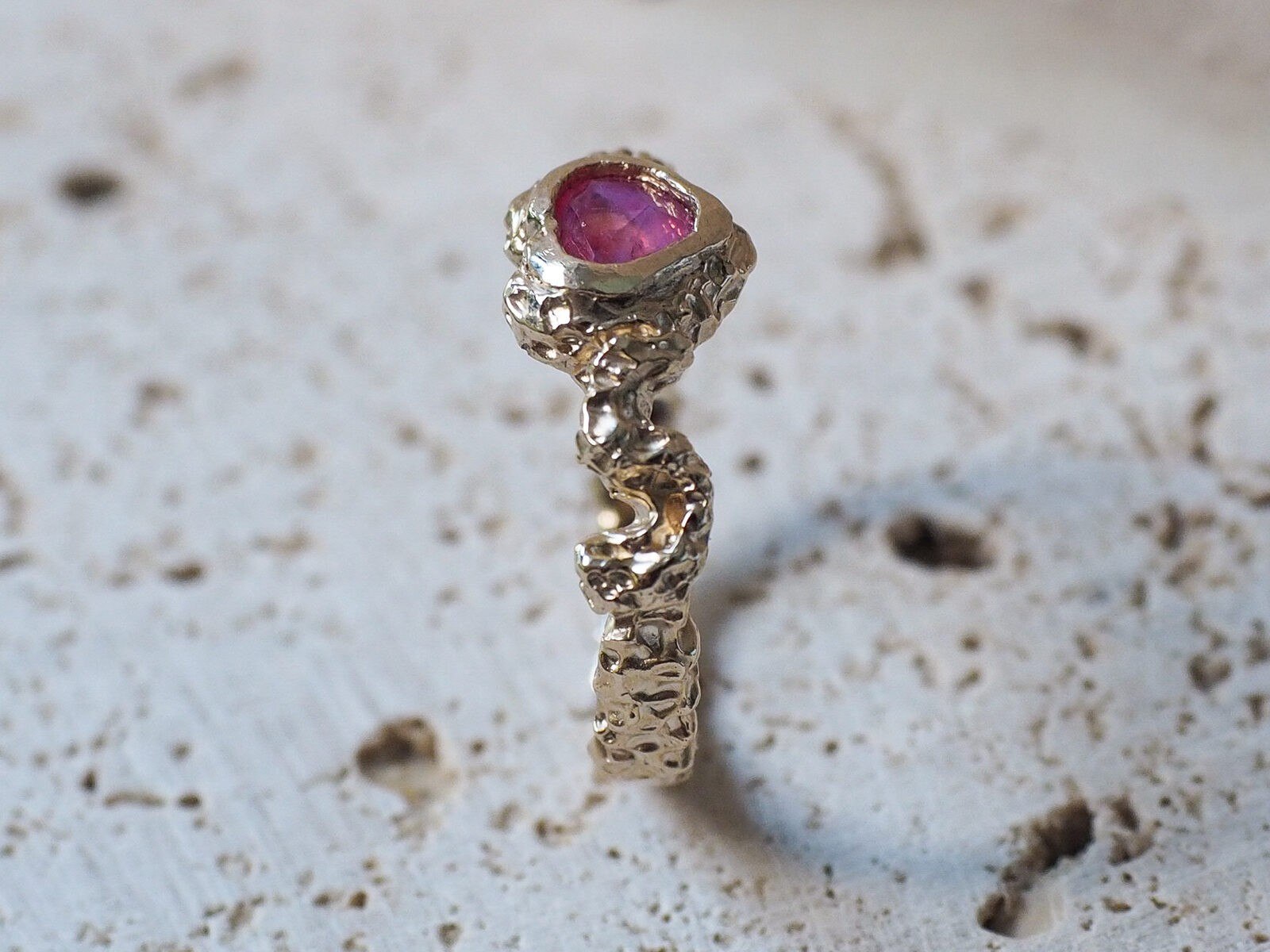 Close-up of the ring’s pink sapphire, set in a textured, handcrafted setting