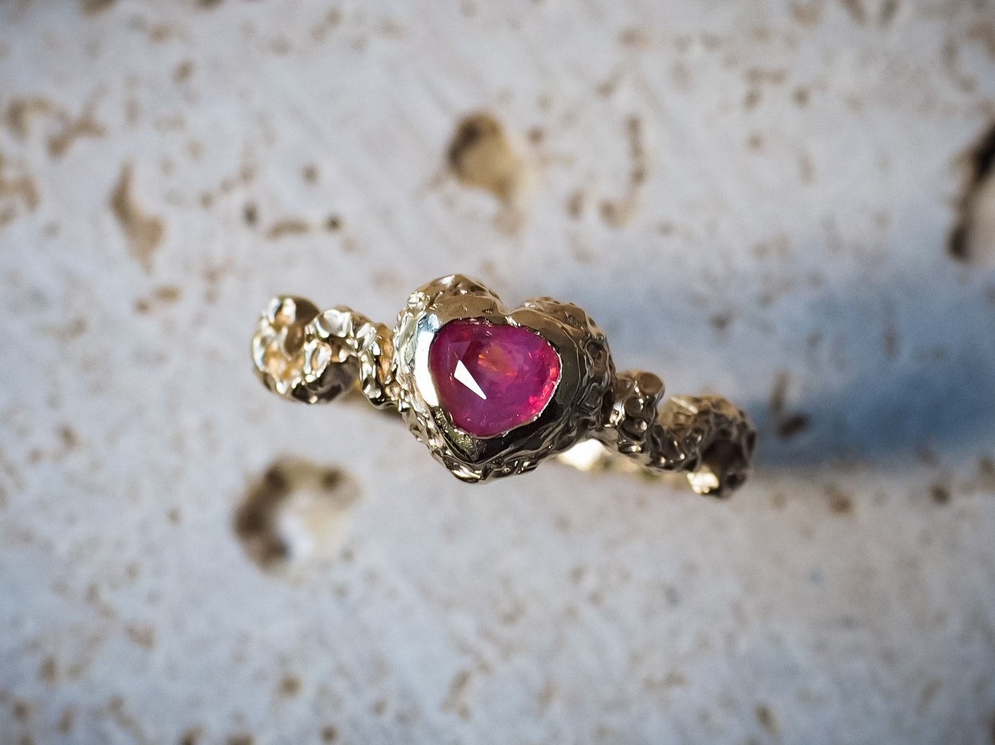 A handcrafted yellow gold ring set with a heart-shaped pink sapphire