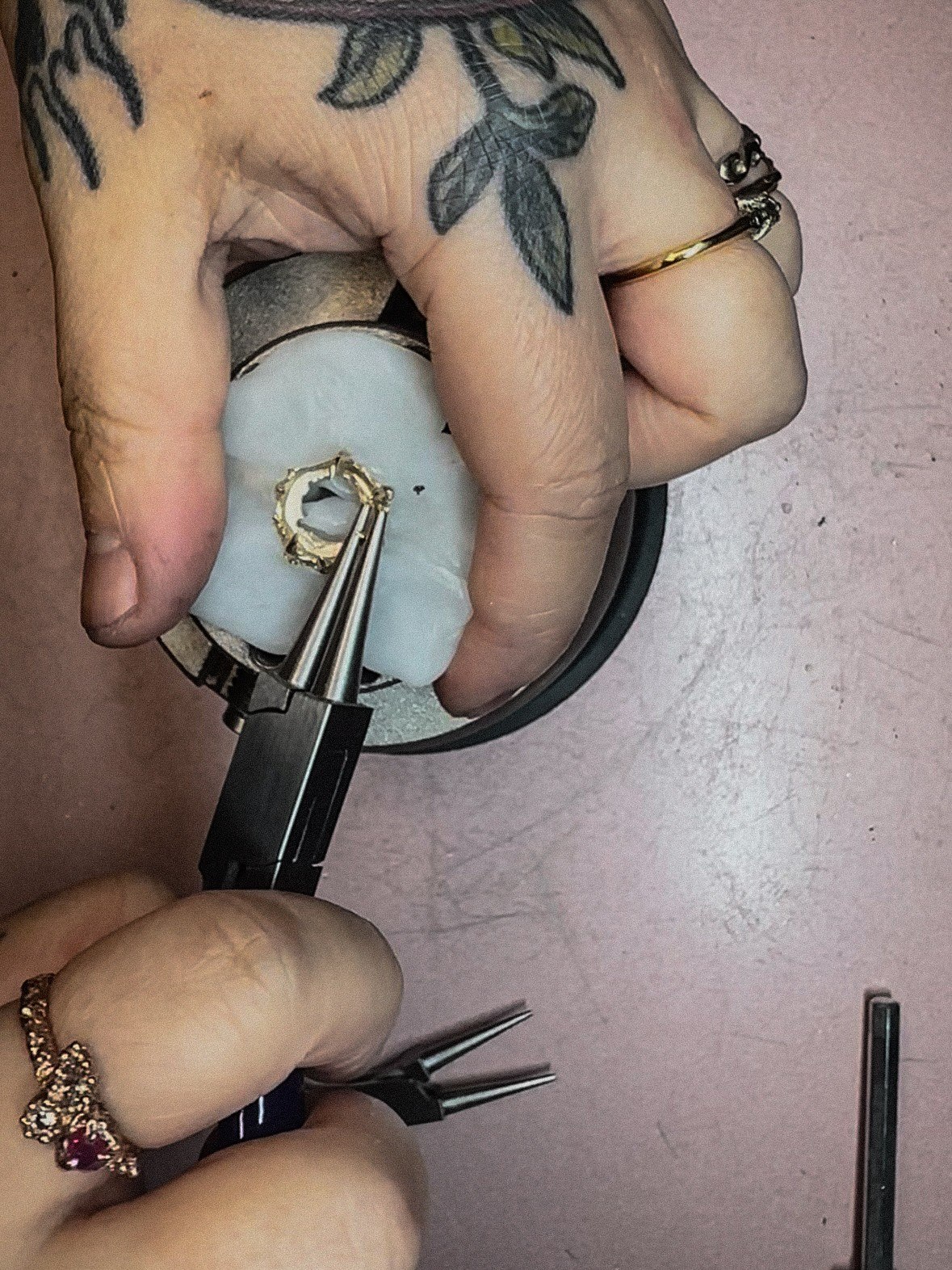 Setting a small stone into a gold ring using fine pliers