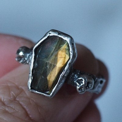 A silver coffin-shaped ring set with labradorite, flashing gold and green