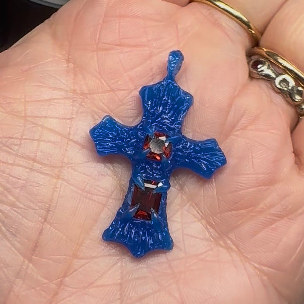 A cross pendant shown in blue wax before casting