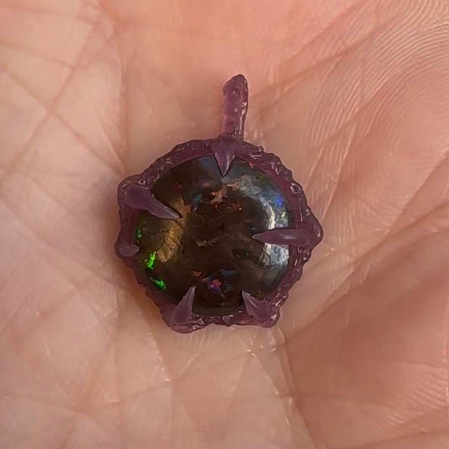 An opal pendant setting shown in purple wax before casting