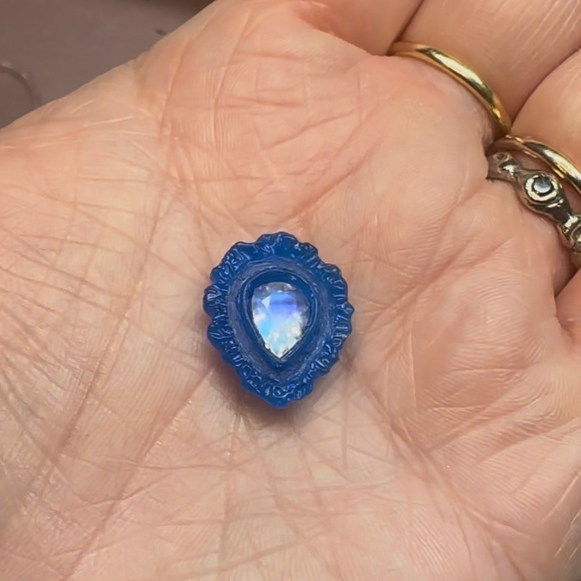A teardrop pendant setting shown in blue wax before casting